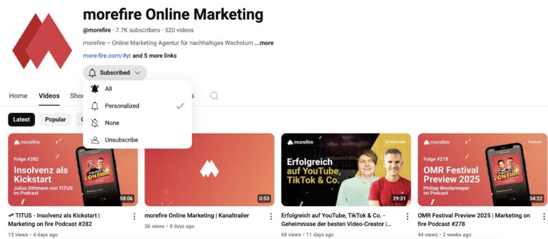 YouTube-Kanal „morefire Online Marketing“ mit 7.7 K Abonnent:innen und 520 Videos. Im Bild ist die Videoübersicht im Tab „Videos“ zu sehen. Das Abo-Icon ist aktiviert und zeigt das Dropdown-Menü mit Optionen wie „All“, „Personalized“ (ausgewählt), „None“ und „Unsubscribe“. Zu den sichtbaren Videos gehören u. a. der Podcast „Insolvenz als Kickstart“, der Kanaltrailer, ein Expertentalk über Video-Erfolg auf YouTube und TikTok sowie eine Vorschau auf das OMR Festival 2025.