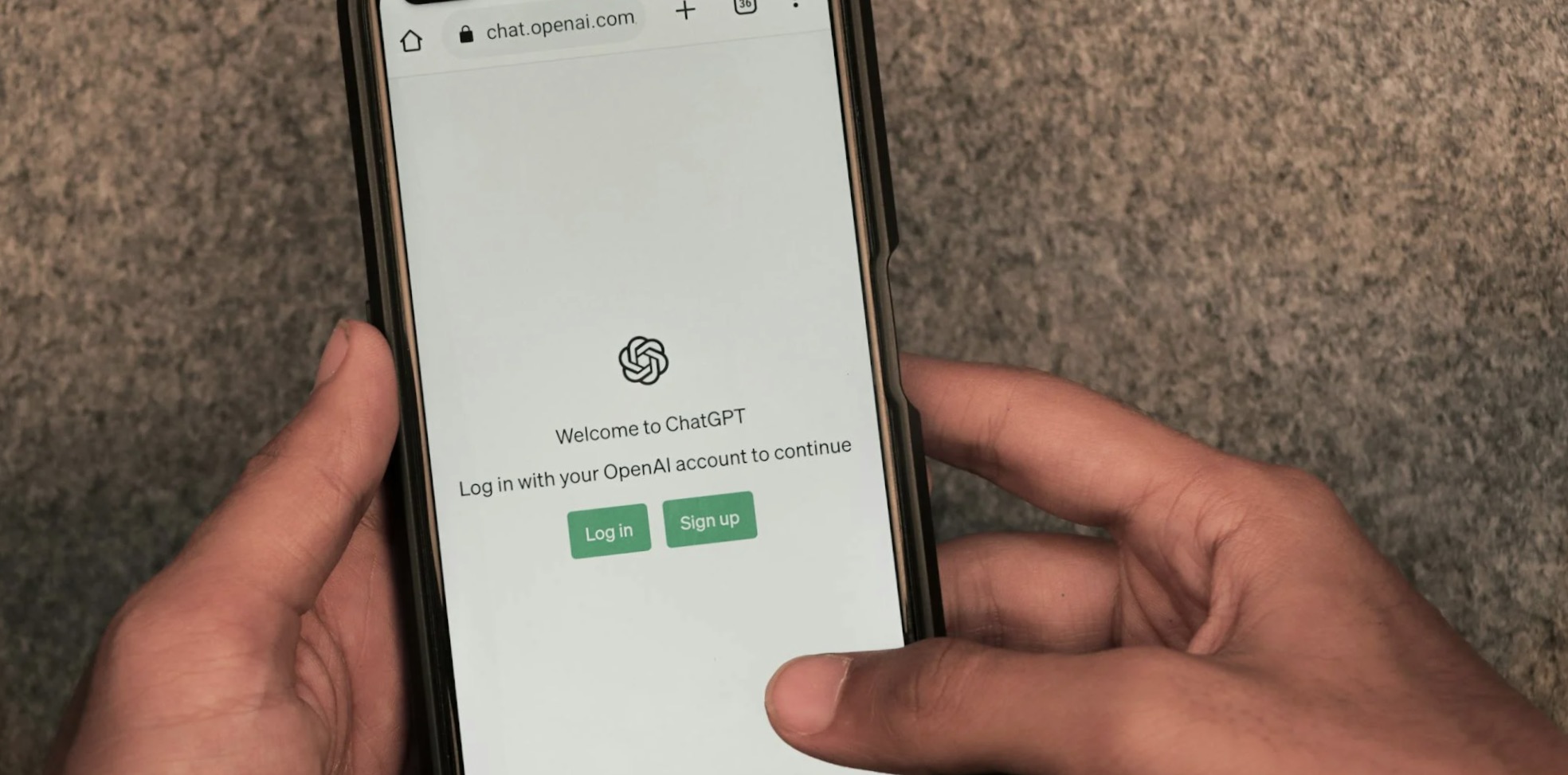 Person hält ein Smartphone mit geöffneter ChatGPT-Anmeldeseite in der Hand.
