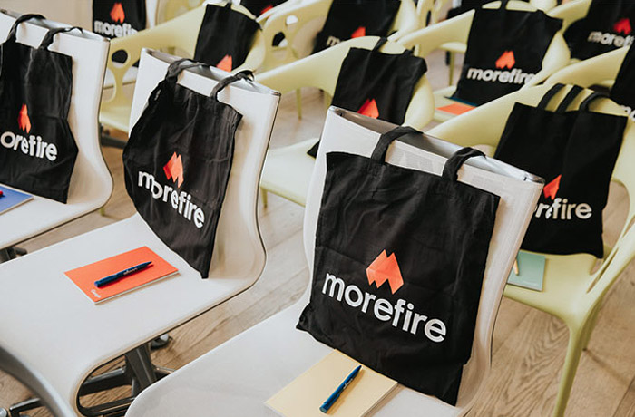 Konferenztaschen von Morefire auf Stühlen bei einer Veranstaltung