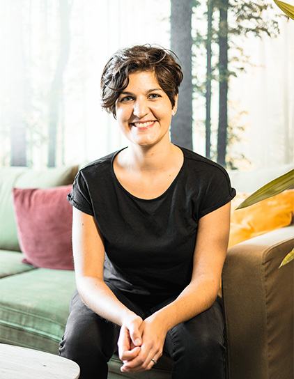 Bild von Ana Isabel Schwaak, Mitarbeiterin bei Morefire, auf einem grünen Sofa sitzend