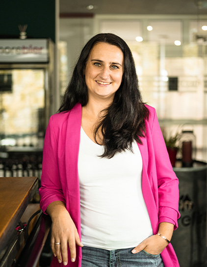 Hanna Mende lächelt in die Kamera und trägt einen pinken Blazer