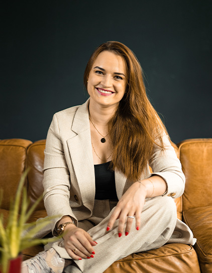 Portrait von Jowita Jezuit-Dejoie, sitzend auf einem braunen Sofa, im Büro von Morefire.
