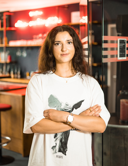 Portrait von Julia Mauszick, stehend mit verschränkten Armen im Büro von Morefire.
