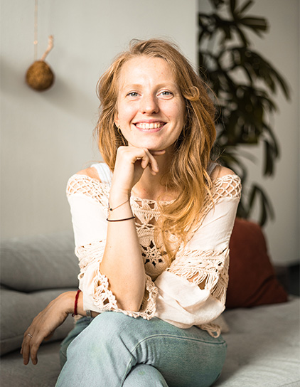 Lea Martin, junge Frau, lächelt in die Kamera, sitzt auf einem Sofa im Büro