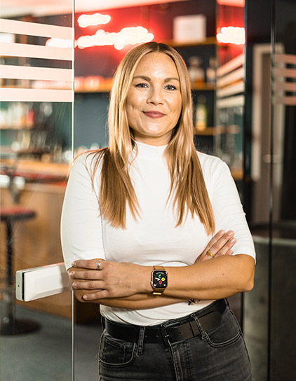 Stephanie Intemann, Teammitglied bei morefire, im modernen Büro-Umfeld mit verschränkten Armen
