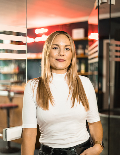 Stephanie Intemann in einem weißen T-Shirt, steht und lächelt in die Kamera