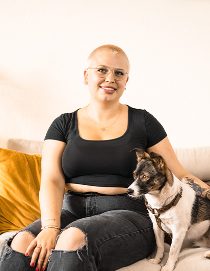 Swantje Veith in einem schwarzen T-Shirt, sitzt mit einem Hund und lächelt in die Kamera