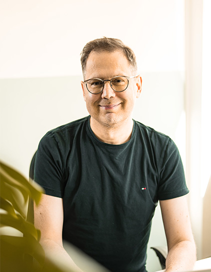 Thorsten Olscha in einem schwarzen T-Shirt, lächelt in die Kamera
