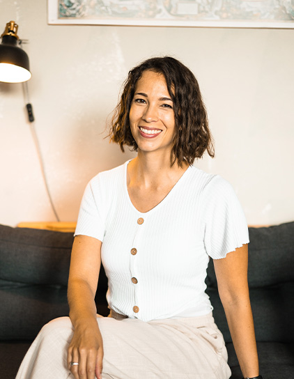 Valerie Khalifeh in einem weißen Hemd, sitzt und lächelt in die Kamera